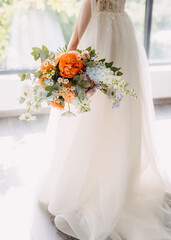 Bride wearing a white dress, holding a vibrant floral bouquet.