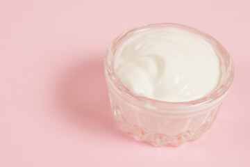 White sauce in a glass saucer on a pink background