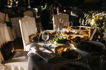Festive banquet aftermath: sunlit table with remnants of a meal and wine in glasses.