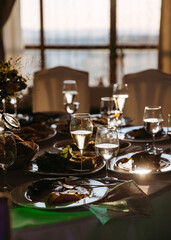 Festive banquet aftermath: sunlit table with remnants of a meal and wine in glasses.