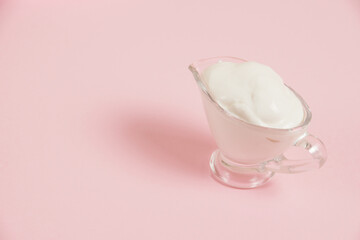 White sauce in a glass saucer on a pink background
