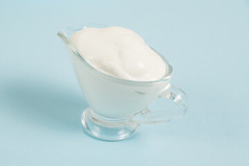 White sauce in a glass saucer on a blue background