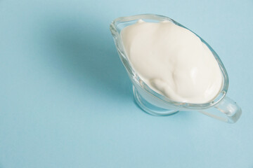 White sauce in a glass saucer on a blue background