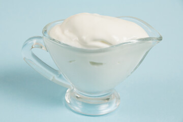 White sauce in a glass saucer on a blue background
