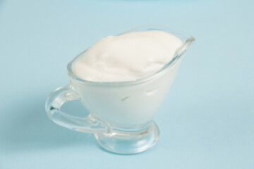 White sauce in a glass saucer on a blue background