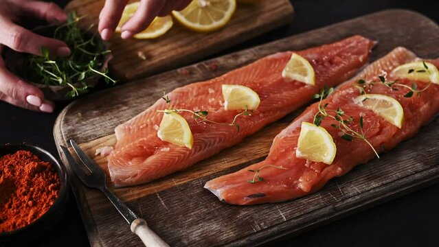 Girl cooker preparing for cookingRaw Fresh trout salmon filet with lemons on wooden board. Fresh uncooked red fish fillet