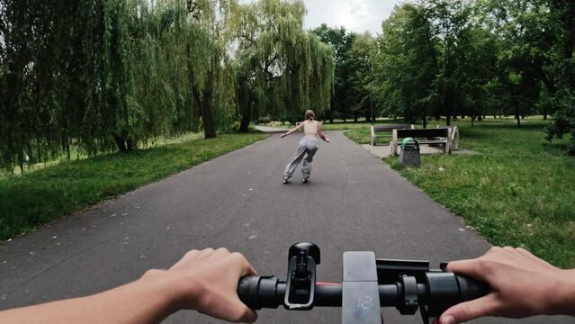 Girl riding electric scooter with rollerscating teenager in park. Friends with modern vehicles enjoying nature outdoors activities