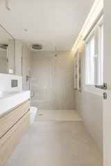 A bathroom with marble-effect tile walls, integrated wall mirror, smooth matte stoneware floors, shower cubicle