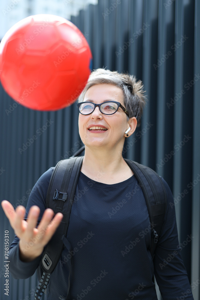 Sticker Mature woman happily engages in outdoor sports training, playing with a ball