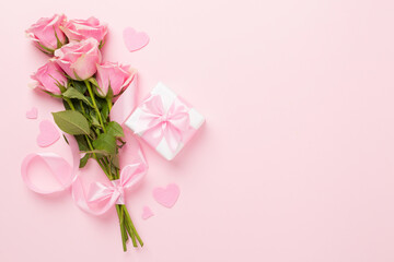 Pink roses with hearts and gift box on color background, top view. Valentines day concept