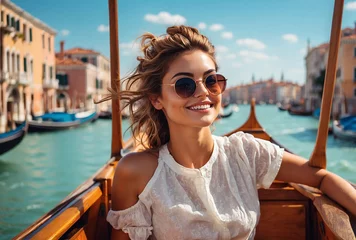Fotobehang A girl in sunglasses and a sundress rides a gondola in Venice © tanya78