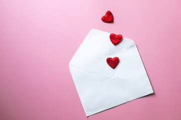 Valentine's Day background. Blank white envelope with red hearts on pink background