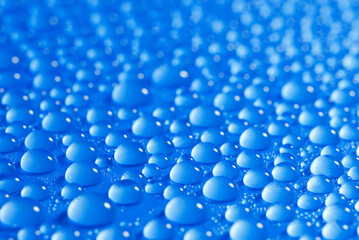 closeup, macro of many water drops, droplets, on a blue surface, background