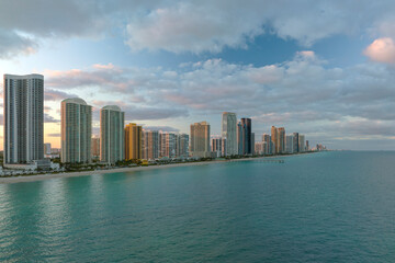 Fototapeta na wymiar Expensive highrise hotels and condos over sandy beachfront on Atlantic ocean shore in Sunny Isles Beach city at sunset. American tourism infrastructure in southern Florida