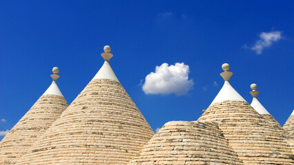 Fototapeta na wymiar closeup of conical roof or cone roof of Trullo House against blue sky and white fluffy cloud, near town of Alberobello, Apulia, Italy, Europe , Trulli