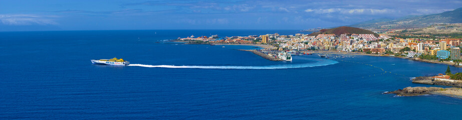 Naklejka na ściany i meble panoramic, panorama town view, city scape of Los Cristianos and rapid ferry Fred Olsen Express, Tenerife, Canary Islands, Spain, Europe