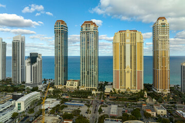 Obraz premium View from above of luxurious highrise hotels and condos on Atlantic ocean shore in Sunny Isles Beach city. American tourism infrastructure in southern Florida