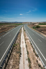 Roads parallel to the horizon in the background of the photograph, with vegetation and signage.