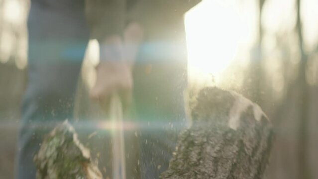 Man chopping firewood outside during sunset