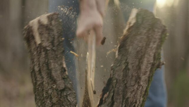 Man chopping firewood outside during sunset