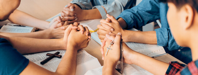 Cropped image of diversity people hand praying together at wooden church on bible book while hold hand together with believe. Concept of hope, religion, faith, god blessing concept. Burgeoning. - obrazy, fototapety, plakaty
