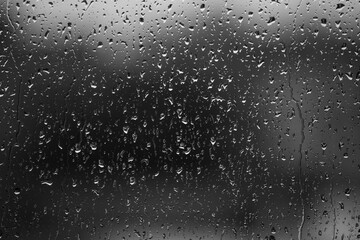 Rain drops on window glass closeup macro. Black and white abstract background texture