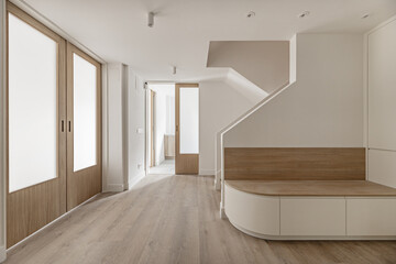 A large hall of a recently renovated modern house with a white oak wooden bench with drawers