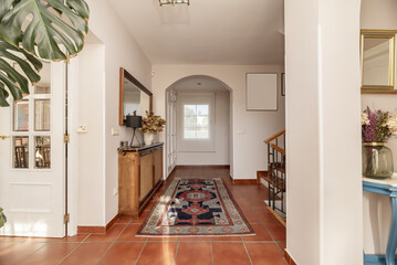 hallway of a single-family home of various heights with brown stoneware floor