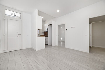 A loft-type home with open spaces with light wooden floors, a small furnished kitchen