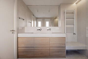 Fototapeta na wymiar Frontal image of a newly built bathroom with a cabinet with chrome-plated steel taps