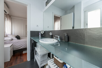 A bathroom with a long tempered glass countertop with white porcelain countertop