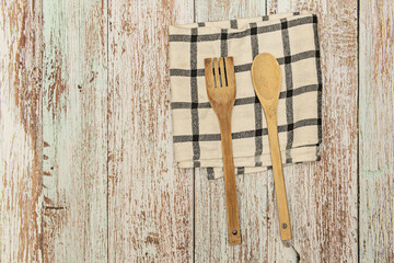 A wooden spoon and fork on a white cloth with gray lines