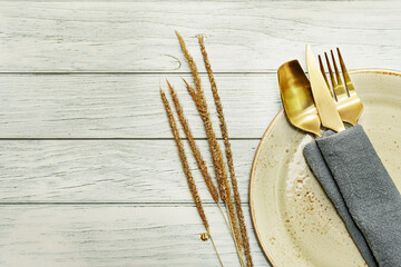 Still life with golden metal cutlery on a plate with a napkin