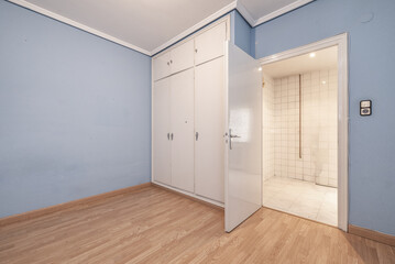 An empty bedroom with a white wooden built-in wardrobe with mezzanines - obrazy, fototapety, plakaty
