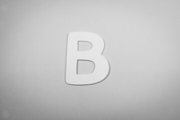 Letter B in wood on a pink background (black and white)
