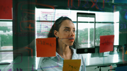 Young hispanic employee writing on colorful sticky notes. Smart businesswoman sharing marketing...