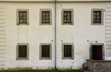 Fototapeta na wymiar Glass windows on white antique wall of old medieval castle in european suburb close up
