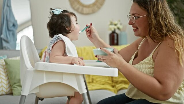 Fun lunch time at home, confident mother and lovely daughter enjoy eating together, smiling and sitting in a casual lifestyle with baby on highchair