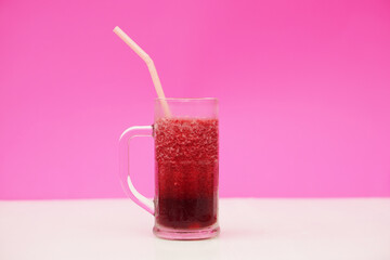 Glass of red fruit smoothie with drinking straw, pink background. Concept, healthy beverage for...