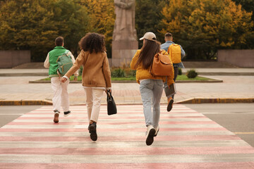 Being late. Group of students running on pedestrian crossing outdoors, back view