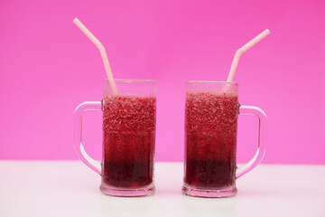 Glasses of red fruit smoothie with drinking straw, pink background. Concept, healthy beverage for...