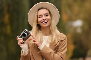 Autumn vibes. Portrait of happy woman with camera outdoors