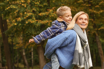 Fototapeta premium Happy mother walking with her son in autumn park. Space for text