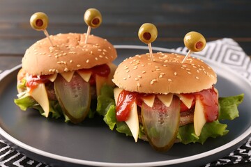 Cute monster burgers on table, closeup. Halloween party food