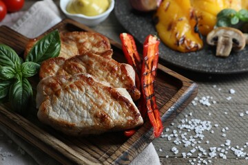 Delicious grilled meat and vegetables served on wooden table, closeup