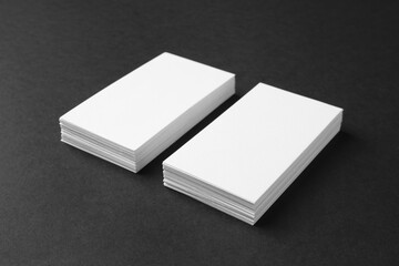 Fototapeta premium Stacks of blank business cards on black background. Mockup for design