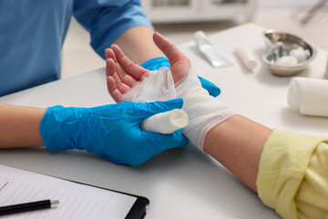 Doctor bandaging patient's burned hand in hospital, closeup