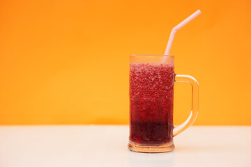Glass of red fruit smoothie with drinking straw, orange background. Concept, healthy beverage for health. Well being and weight loss menu. Homemade refreshing drinks. High fibers, detox.              