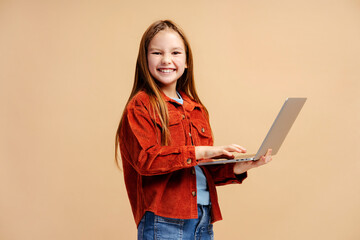 Portrait of beautiful smiling girl wearing casual clothes, holding laptop, doing homework