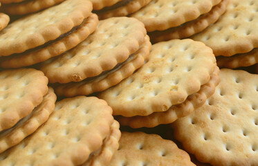 Detailed picture of round sandwich cookies with coconut filling. Background image of a close-up of several treats for tea